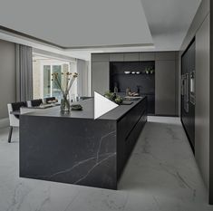 a modern kitchen with marble counter tops and black cabinets, along with an island in the middle