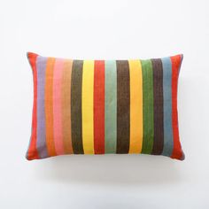 a multicolored striped pillow sitting on top of a white wall