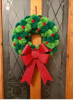 a green wreath with red bows hanging on a door