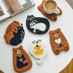 four different animal coasters sitting on top of a table next to a cup of coffee