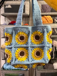 a blue crocheted bag with sunflowers on it hanging from a rack