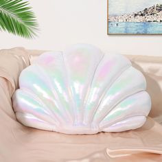 a white shell shaped pillow sitting on top of a couch