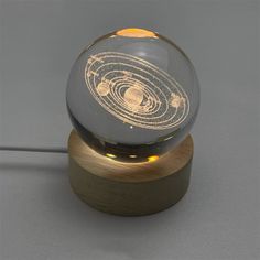 a glass ball with a wooden base on a gray surface and an orange light in the middle