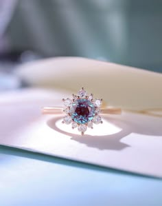 an opal and diamond ring sitting on top of a piece of paper