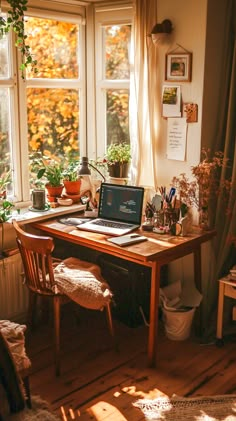 an open laptop computer sitting on top of a wooden desk in front of a window