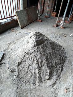 a pile of dirt sitting on top of a cement floor next to a building under construction