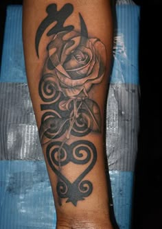 a black and white rose tattoo on the left arm with swirly lines around it