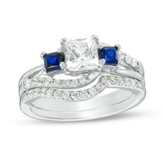 three stone engagement ring set with blue and white sapphire stones on the sides, in 18k white gold