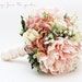 a bridal bouquet with pink and white flowers on the bottom, in front of a white background