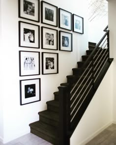 black and white photographs hang on the wall next to a stair case in a home