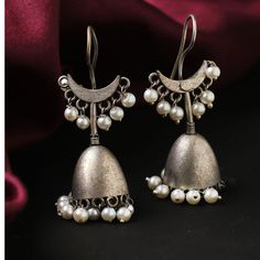 "Introducing our exquisite \"Oxidized Silver Plate Hook Drop Jhumka Jhumki Ethnic Earrings,\" a captivating blend of traditional charm and contemporary style. Elevate your jewelry collection with these intricately crafted earrings designed for women who appreciate the beauty of cultural aesthetics. These stunning jhumka jhumki earrings feature a unique oxidized silver plate, adding a vintage touch that complements both modern and ethnic ensembles. The carefully designed hooks enhance the overall appeal, providing a secure and comfortable fit. The fusion of tradition and trend is beautifully showcased in the delicate pearl embellishments, adding a touch of elegance and grace to these statement earrings. Whether you're dressing up for a special occasion or looking to add a touch of glamour t Luxury Traditional Jhumkas With Zari Work, Cheap Festive Metal Jhumkas, Luxury Traditional Jhumkas With Intricate Design, Luxury Traditional Jhumkas For Wedding, Luxury Traditional Jhumkas, Luxury Silver Temple Jewelry Jhumkas, Chandbali Earrings With Bells For Festivals, Traditional Brass Jhumkas For Navratri, Brass Jhumkas For Rituals And Festivals