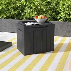 a bowl of fruit is sitting on top of a small table with a yellow and white striped rug