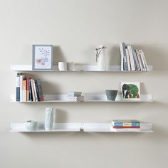 two white shelves with books and vases on them