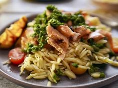 a plate with pasta, broccoli and meat on it sitting on a table