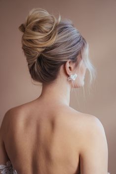 a woman in a wedding dress with her back turned to the camera and wearing earrings