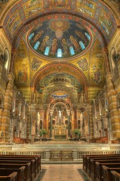 the inside of a church with many pews and paintings on the walls, along with stained glass windows