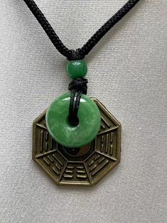 "Green Jade Donut with Taiji Bagua and Yin Yang charm Necklace. Jade donut means Wealth, Peaceful and Protection. Taiji Bagua with 8 Trigrams and Yin Pang Charm for live in harmony with the energies. Good for Feng Shui. This is a good luck necklace special for you, families and friends. Necklace Length is adjustable up to 24\". Material : Jade Donut, Jade Ball , Brass Coin and Nylon Cord Jade color : Green, Bagua color : Brown , Necklace Cord : Black and Red Size : Jade Donut - 15mm round, Jade 8 Trigrams, Green Jade Necklace, Yin Yang Charm, Friends Necklace, Luck Necklace, Good Luck Necklace, Jade Color, Silk Bag, Kwan Yin