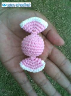 a small crocheted pink and white object in the palm of someone's hand