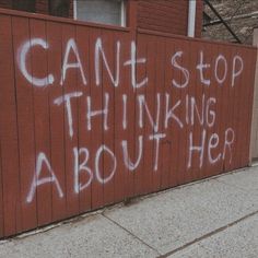 graffiti written on the side of a red fence that says can't stop thinking about her