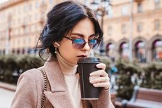 a woman wearing sunglasses and holding a coffee cup