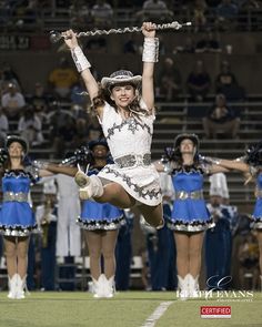 a cheerleader is in the air with her hands up as she performs at a football game