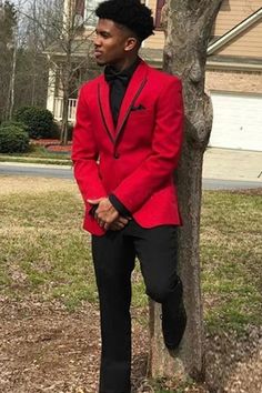 a man in a red suit leaning against a tree