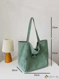 a green bag sitting on top of a white table next to a lamp and shade