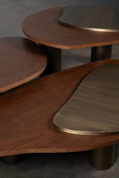 three wooden tables sitting on top of each other in front of a gray wall and floor