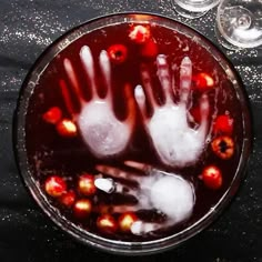 a glass bowl filled with liquid and two hand prints on the bottom, surrounded by wine glasses