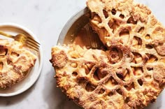 a pie on a plate next to a fork and bowl with another pie in it