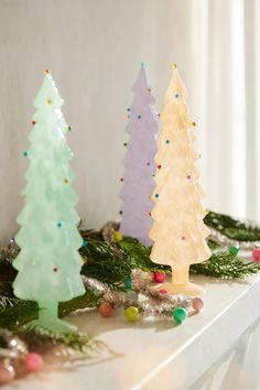 three plastic christmas trees sitting on top of a mantle