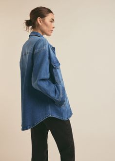 a woman wearing a denim jacket and black pants