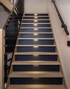 a set of stairs leading up to a second floor with black railings and wooden handrails