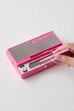 a person holding a pink radio in their left hand and the other hand on top of it