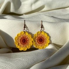 yellow and red crocheted flower earrings on white fabric