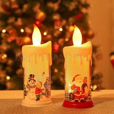 two lit candles sitting on top of a table next to a christmas tree with lights