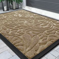 a door mat that is on the ground in front of a house with a plant