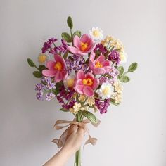 a person holding a bouquet of flowers in their left hand, with the other hand reaching for it