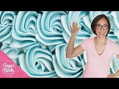 a woman standing in front of a wall made out of blue flowers with her hands up