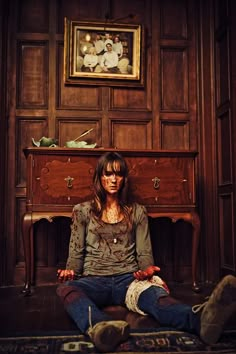 a woman sitting on the floor in front of a dresser