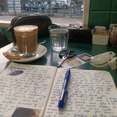 an open notebook sitting on top of a table next to a cup of coffee