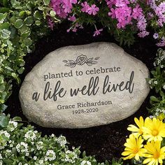 a memorial stone surrounded by flowers and greenery with the words, planted to celebrate a life well lived