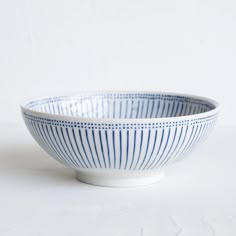 a blue and white striped bowl sitting on top of a white tableclothed surface