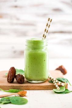 a green smoothie in a mason jar with two straws