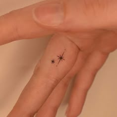 a person's hand with a tiny star tattoo on it