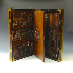 an open wooden box with many different tools in it's opening doors and handles