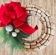 a christmas wreath made out of wine corks with a red bow and pine cones