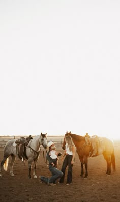 a man is standing next to two horses in an open field with the sun shining on them