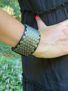 Wide leather cuff bracelet with overlapping flat metal studs for men and women with adjustable snap closure. This bracelet has a modern urban look. Fits wrists from 6.5" to 8.5". Width is about 1.5". Adjustable Punk Cuff Bracelet With Rivets, Punk Adjustable Cuff Bracelet With Rivets, Punk Style Adjustable Cuff Bracelet With Rivets, Punk Cuff Bracelets With Rivets, Trendy Festival Bracelets With Rivets, Edgy Adjustable Cuff Leather Bracelet, Trendy Adjustable Bracelets With Rivets, Metal Leather Bracelet With Rivets For Festival, Adjustable Black Cuff Bracelet With Rivets