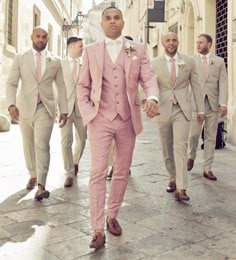 a group of men in suits and ties walking down the street with one man wearing a pink suit